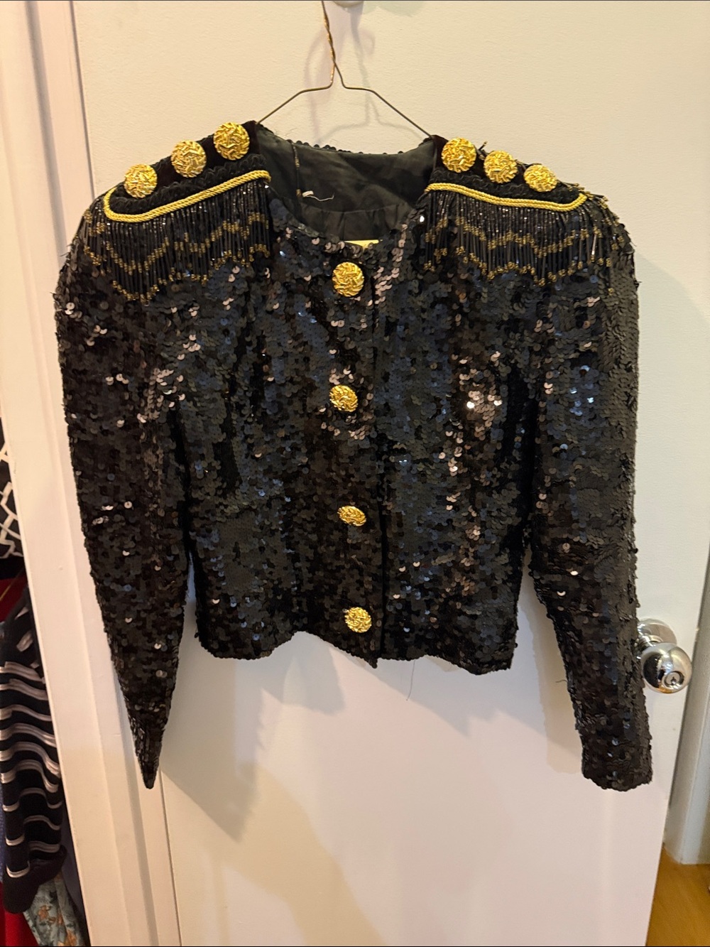 Black cropped Sequin jacket with epithets on shoulder. Gold buttons.